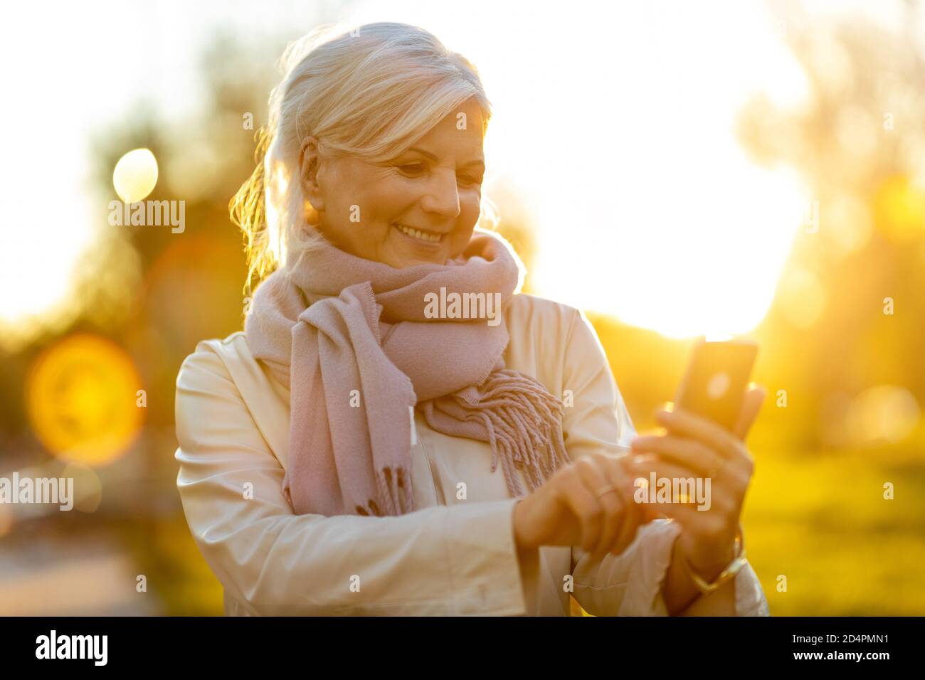 Donna anziana che usa il telefono cellulare all'aperto in autunno Foto Stock