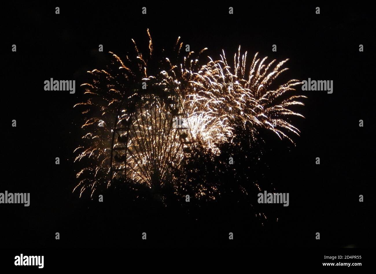 Una ruota di ferro davanti a fuochi d'oro, che illumina la notte Foto Stock