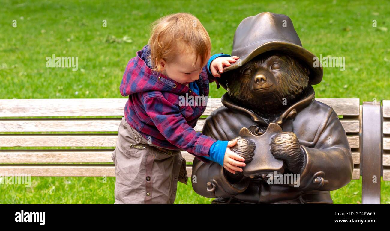 Un toddler che cerca di portare un panino di marmellata di orsi imbottiti a Leicester Square, Londra Foto Stock