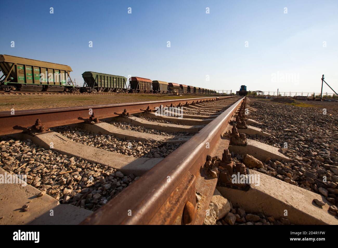 Concimi fosfato pianta. Stazione ferroviaria caricatrice di fertilizzanti. Carri tramoggia verdi all'orizzonte. Primo piano delle guide in primo piano. Foto Stock