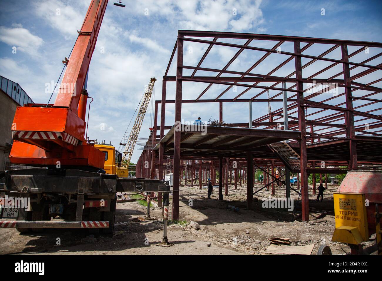 Shymkent/Kazakhstan - Aprile 27 2012: Costruzione di un nuovo edificio industriale. Gru mobile e struttura metallica con lavoratori. Foto Stock