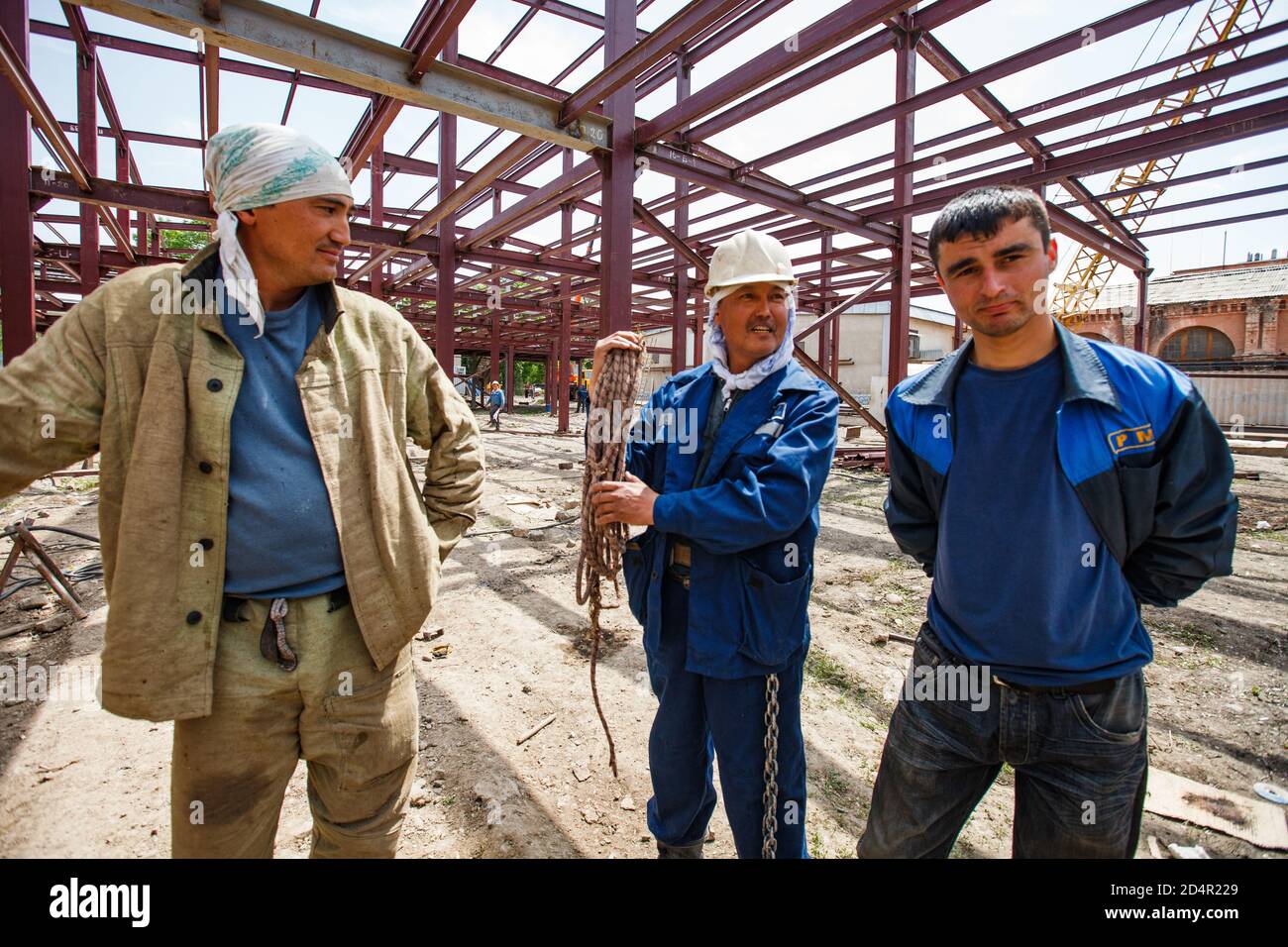 Shymkent/Kazakhstan - Aprile 27 2012: Costruzione di un nuovo edificio industriale. Lavoratori che posano sullo sfondo della struttura metallica dell'edificio. Foto Stock