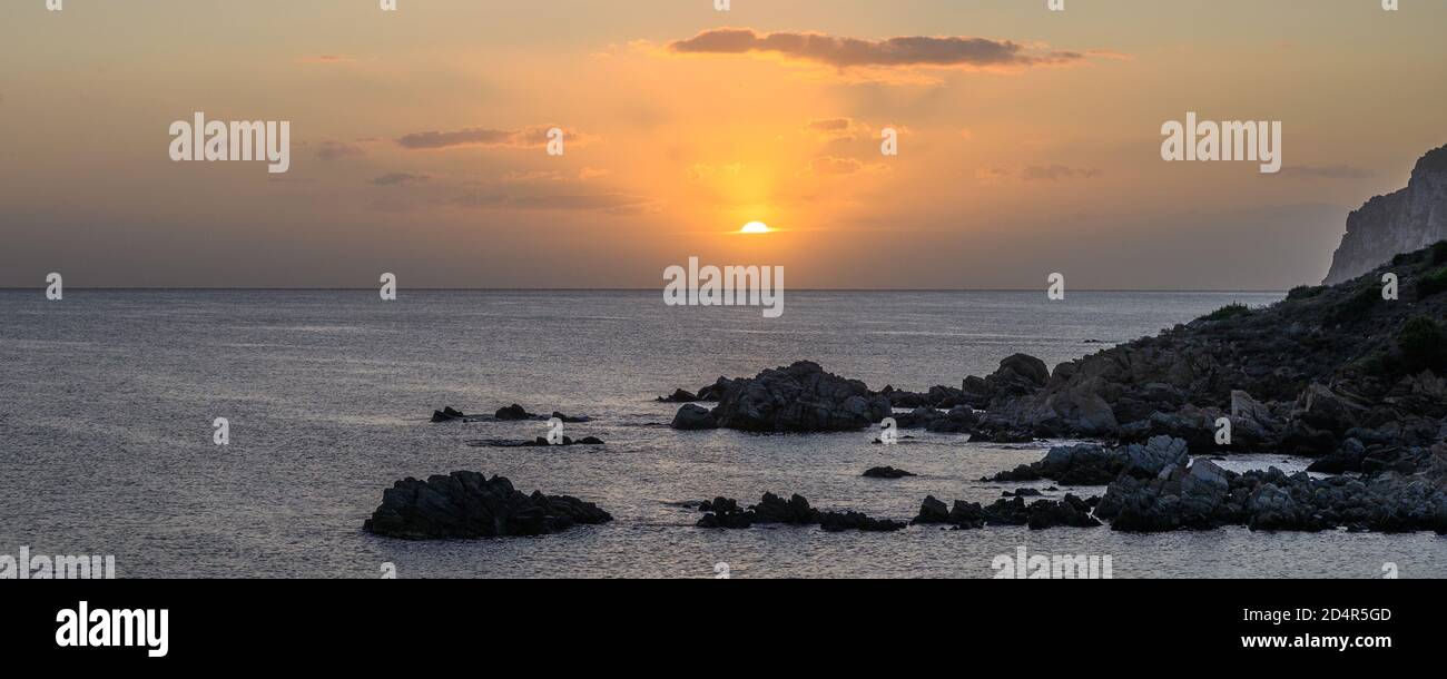 Panorama Dawn sul mare, i raggi del sole si riflettono nelle nuvole, in primo piano una riva rocciosa, copia spazio Foto Stock