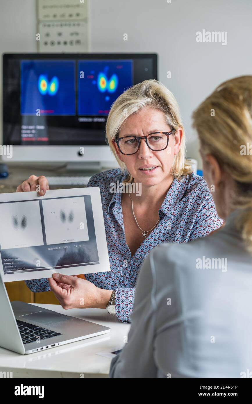 Medico a discutere di una ghiandola tiroidea scintigramma con un paziente femmina. Foto Stock