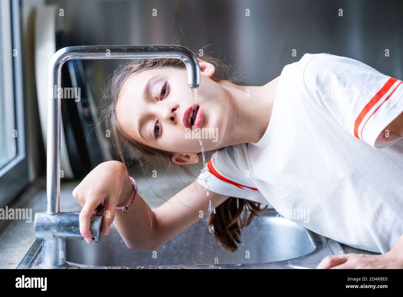 ragazza di 12 anni che beve acqua di rubinetto. Foto Stock