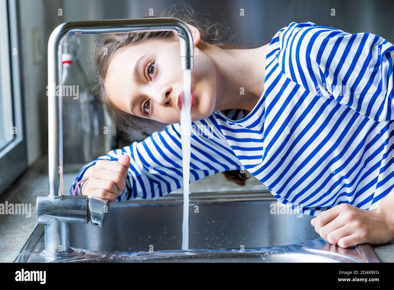 ragazza di 12 anni che beve acqua di rubinetto. Foto Stock