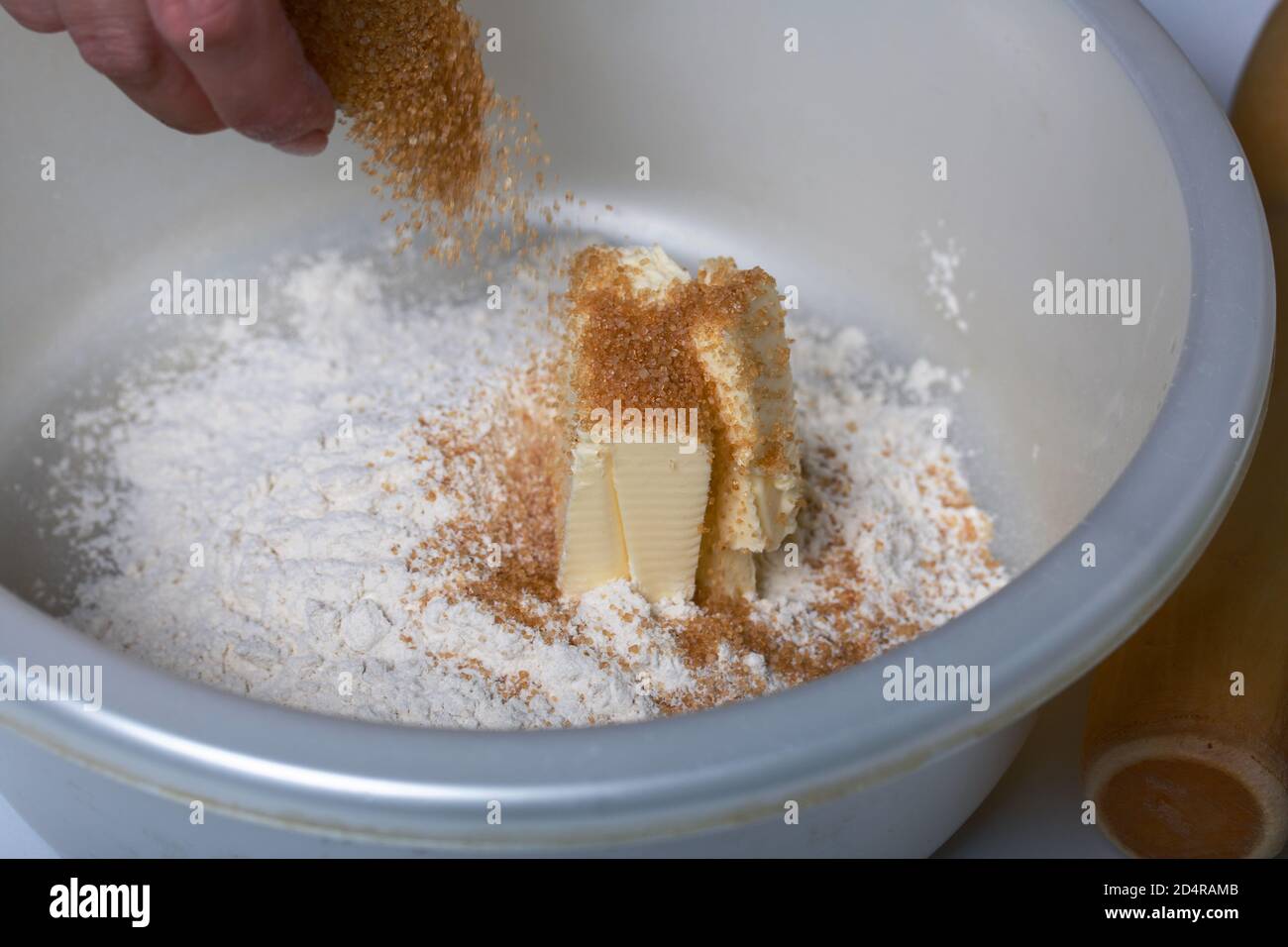 Una donna mescola burro, zucchero e farina in un recipiente. Torta di Levington, fasi di preparazione. Foto Stock