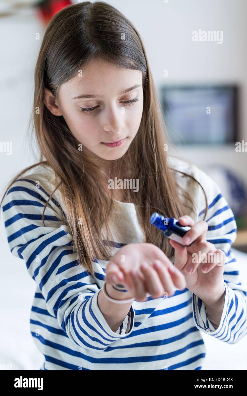 ragazza di 10 anni che applica l'olio essenziale sulla sua pelle. Foto Stock