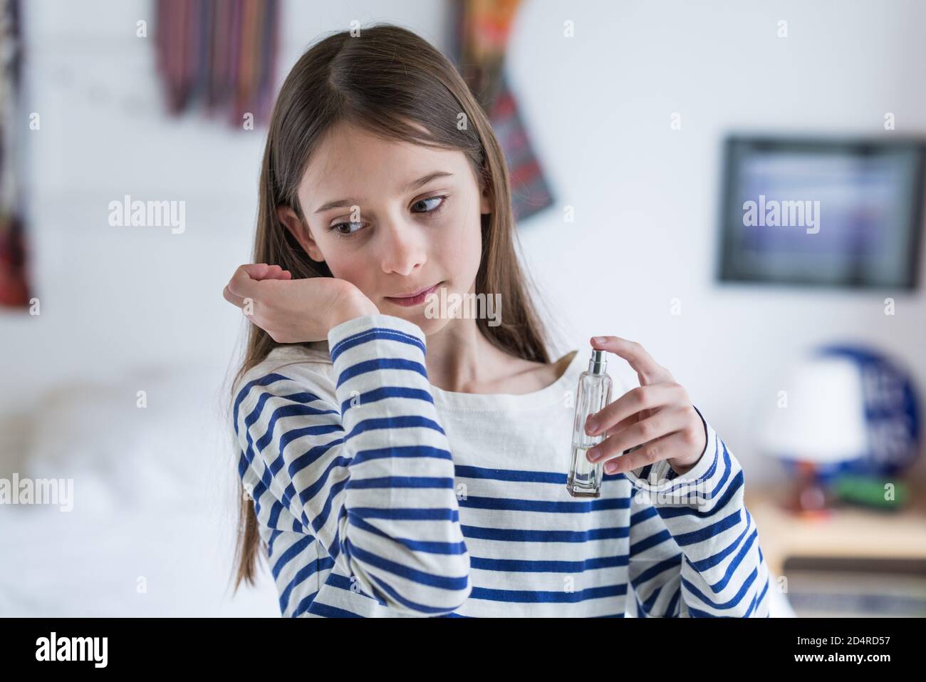 ragazza di 10 anni che applica il perfum. Foto Stock