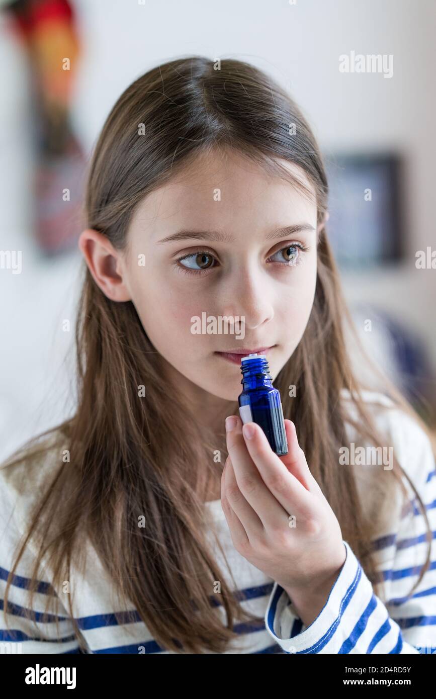 ragazza di 10 anni che odora una bottiglia di olio essenziale. Foto Stock