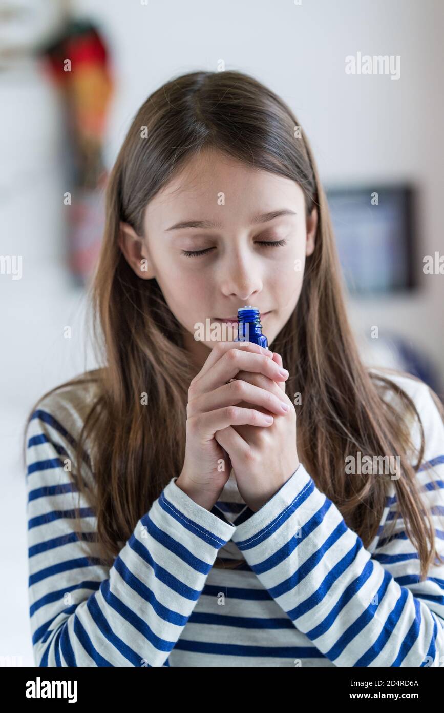 ragazza di 10 anni che odora una bottiglia di olio essenziale. Foto Stock