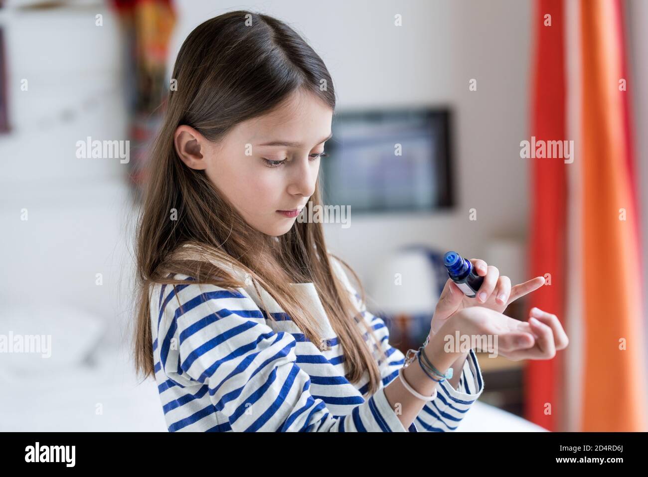 ragazza di 10 anni che applica l'olio essenziale sulla sua pelle. Foto Stock