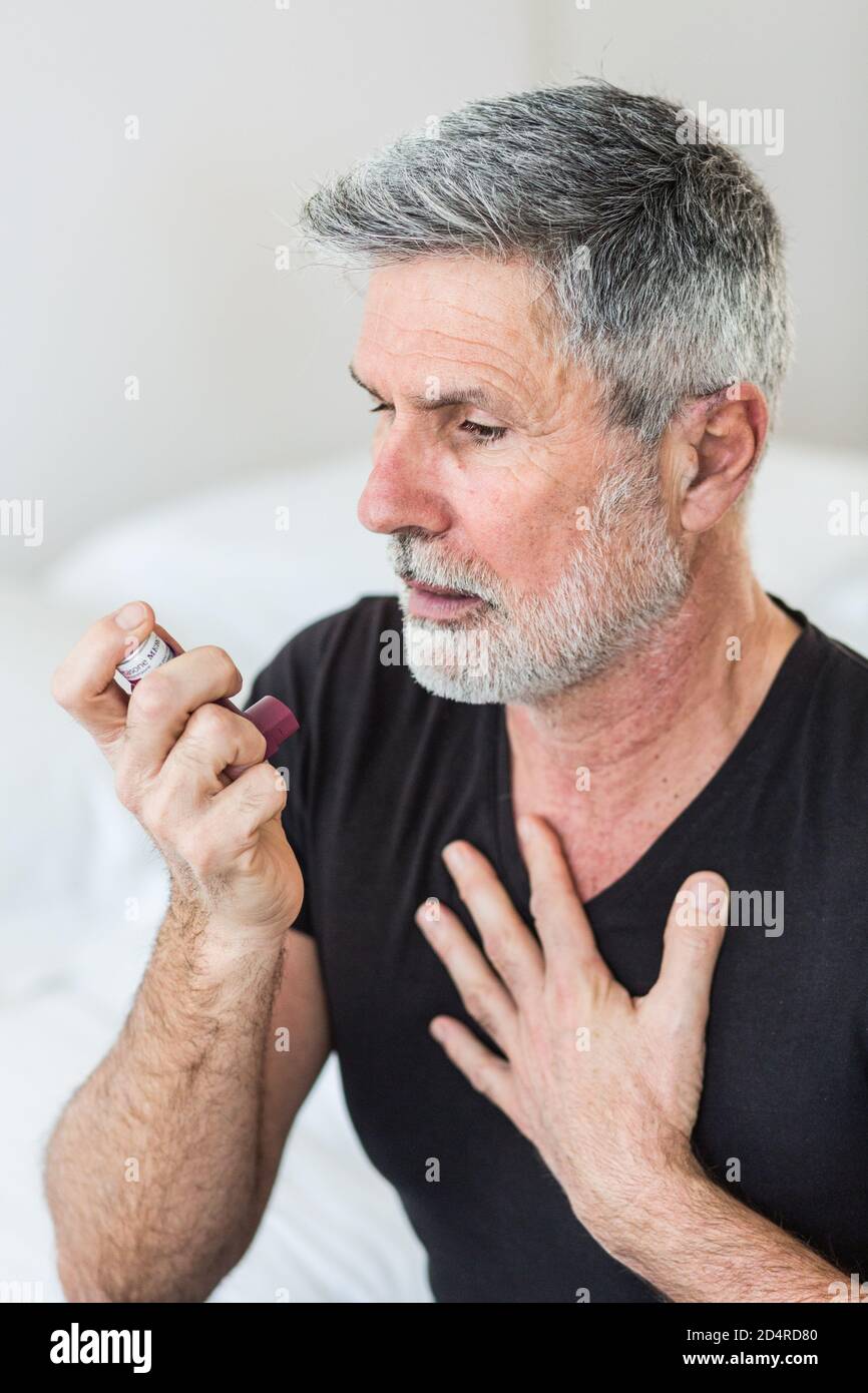 Uomo che utilizza un inalatore durante un attacco d' asma. Foto Stock