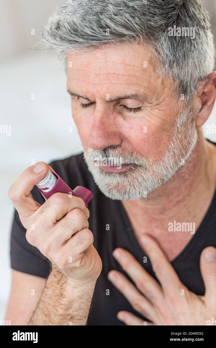 Uomo che utilizza un inalatore durante un attacco d' asma. Foto Stock