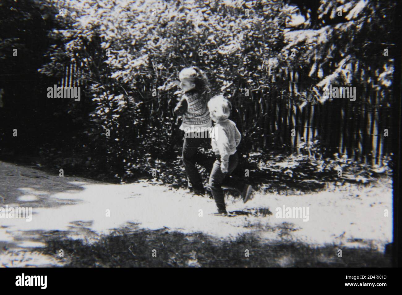 Bella fotografia in bianco e nero degli anni '70 di due giovani ragazze che girano intorno al giardino del cortile. Foto Stock