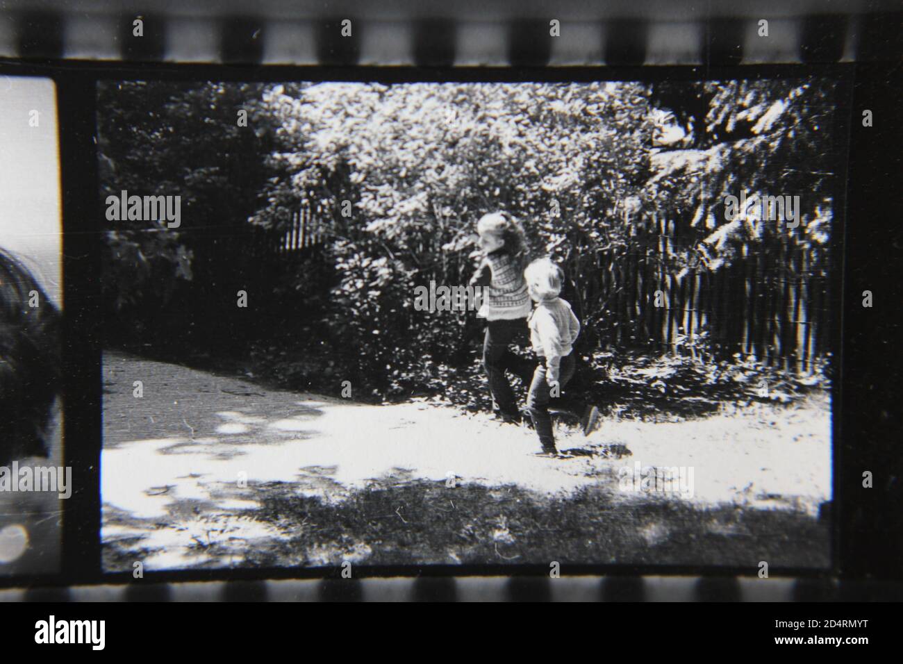 Bella fotografia in bianco e nero degli anni '70 di due giovani ragazze che girano intorno al giardino del cortile. Foto Stock