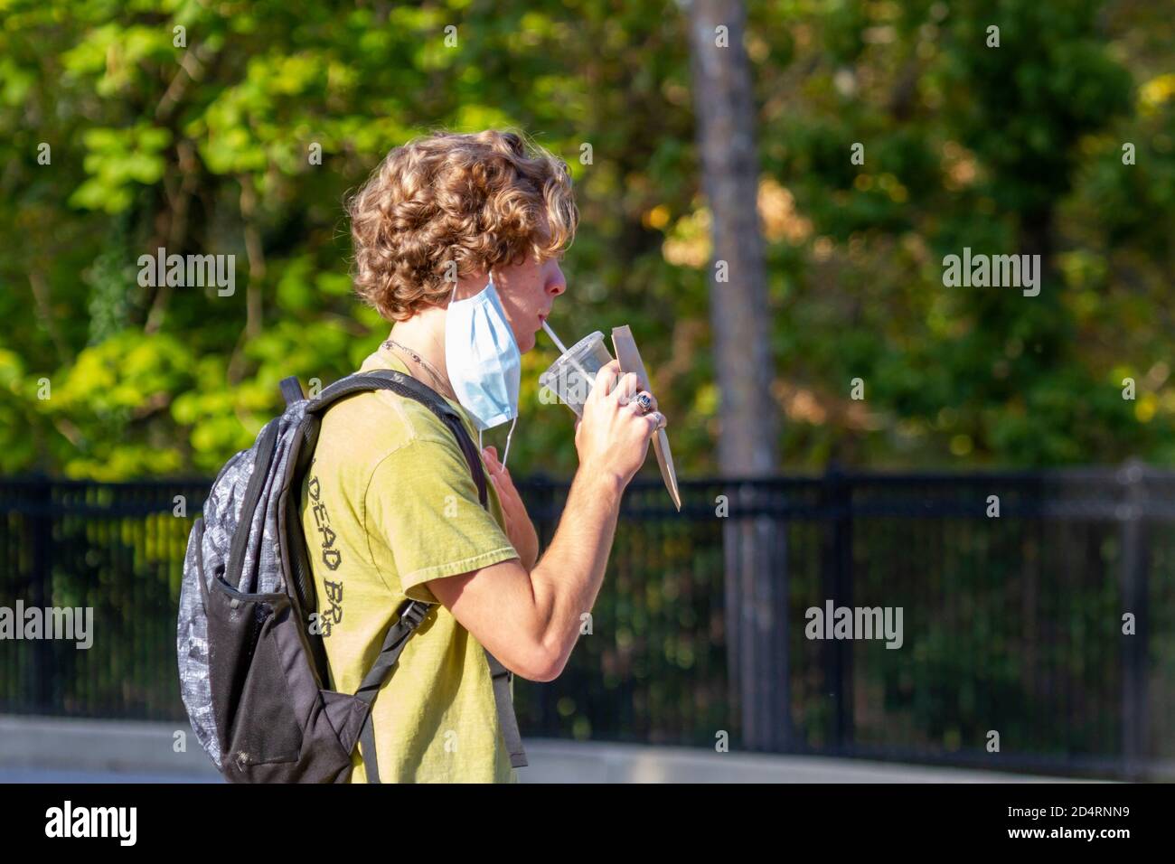 Ellicott City, MD, USA 10/07/2020: Un uomo caucasico biondo che indossa la maschera facciale a causa di COVID-19 sta rimuovendo temporaneamente parte della sua maschera per prendere un sorso Foto Stock