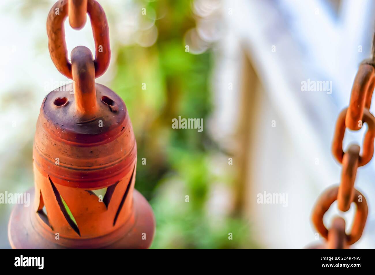 Un manufatto da giardino contenente una campana in argilla è sospeso nell'aria da una catena in ceramica/argilla/terracotta. Foto Stock