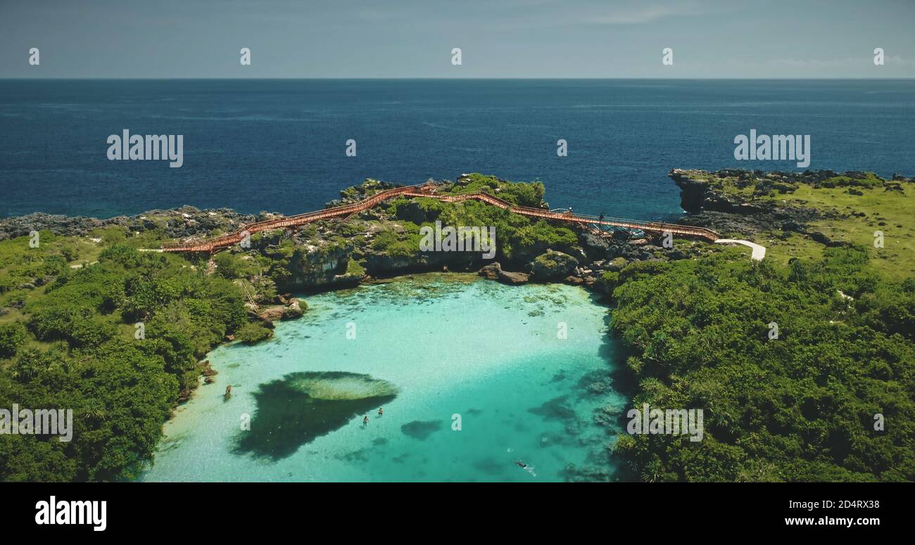 Resort tropicale nel paesaggio turchese del lago Weekuri con verde giungla foresta e erba. Le persone si rilassano e nuotano nella laguna di acqua salata presso la vicina costa rocciosa della baia di mare dell'Indonesia, Asia Foto Stock