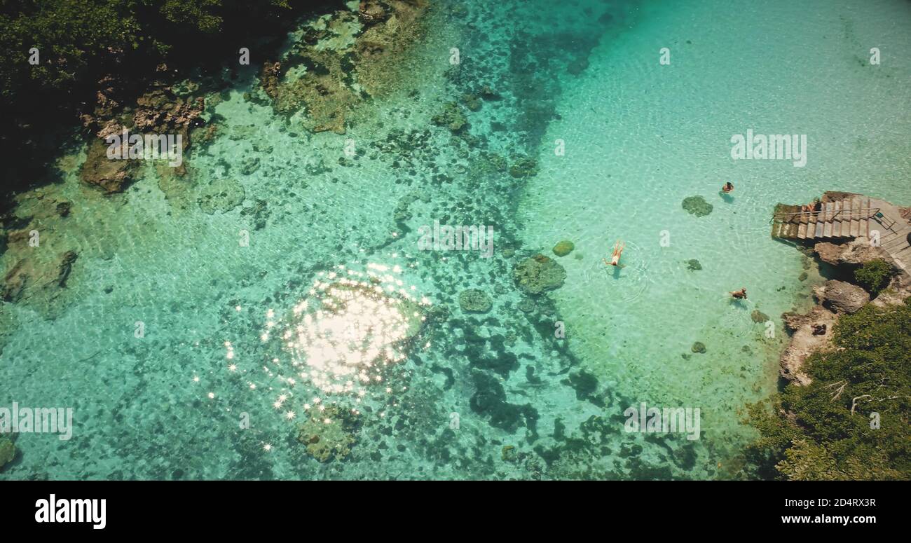 Il sole che si riflette e frizzante si può abbattere al lago d'acqua salata smeraldo. La gente nuota e gioca nella laguna tropicale poco profonda con acqua cristallina. Relax sereno per vacanze estive a Sumba Island, Indonesia Foto Stock