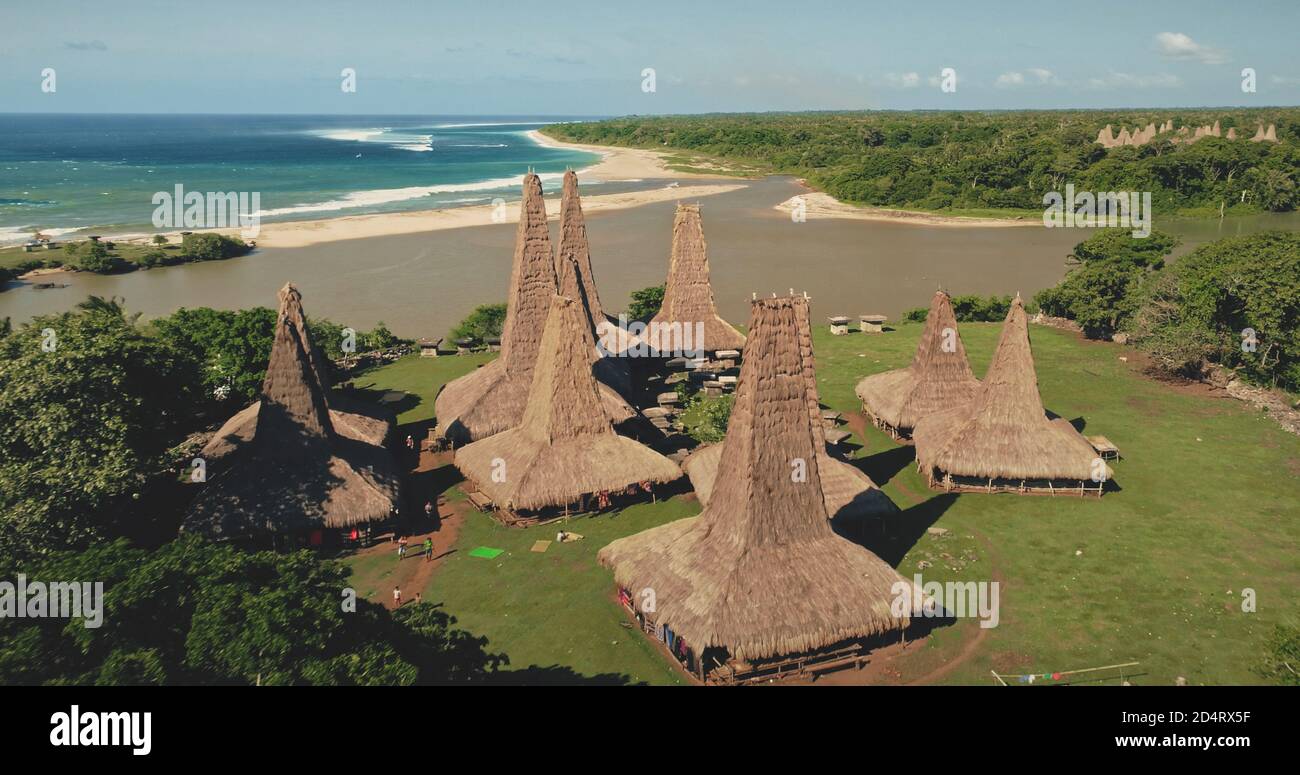 Verde foresta con case tradizionali villaggio sulla spiaggia di sabbia oceano vista aerea. Paesaggio naturale tropicale in un insediamento di lunga tradizione in estate. Alberi verdi, erba con tetti ornately cottage Foto Stock