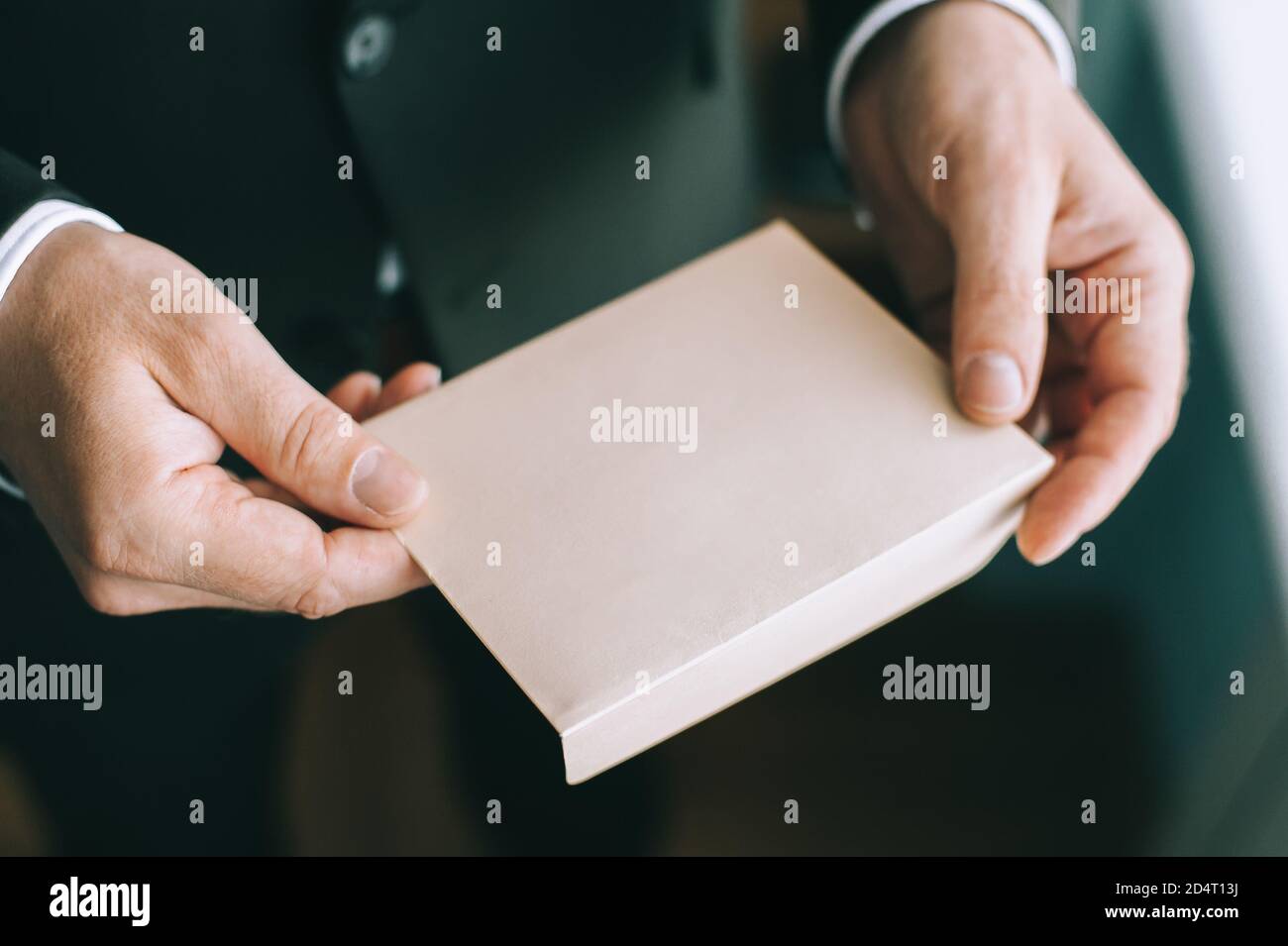 Primo piano delle mani di un uomo serio adulto che tiene una busta bianca senza iscrizioni. Foto Stock