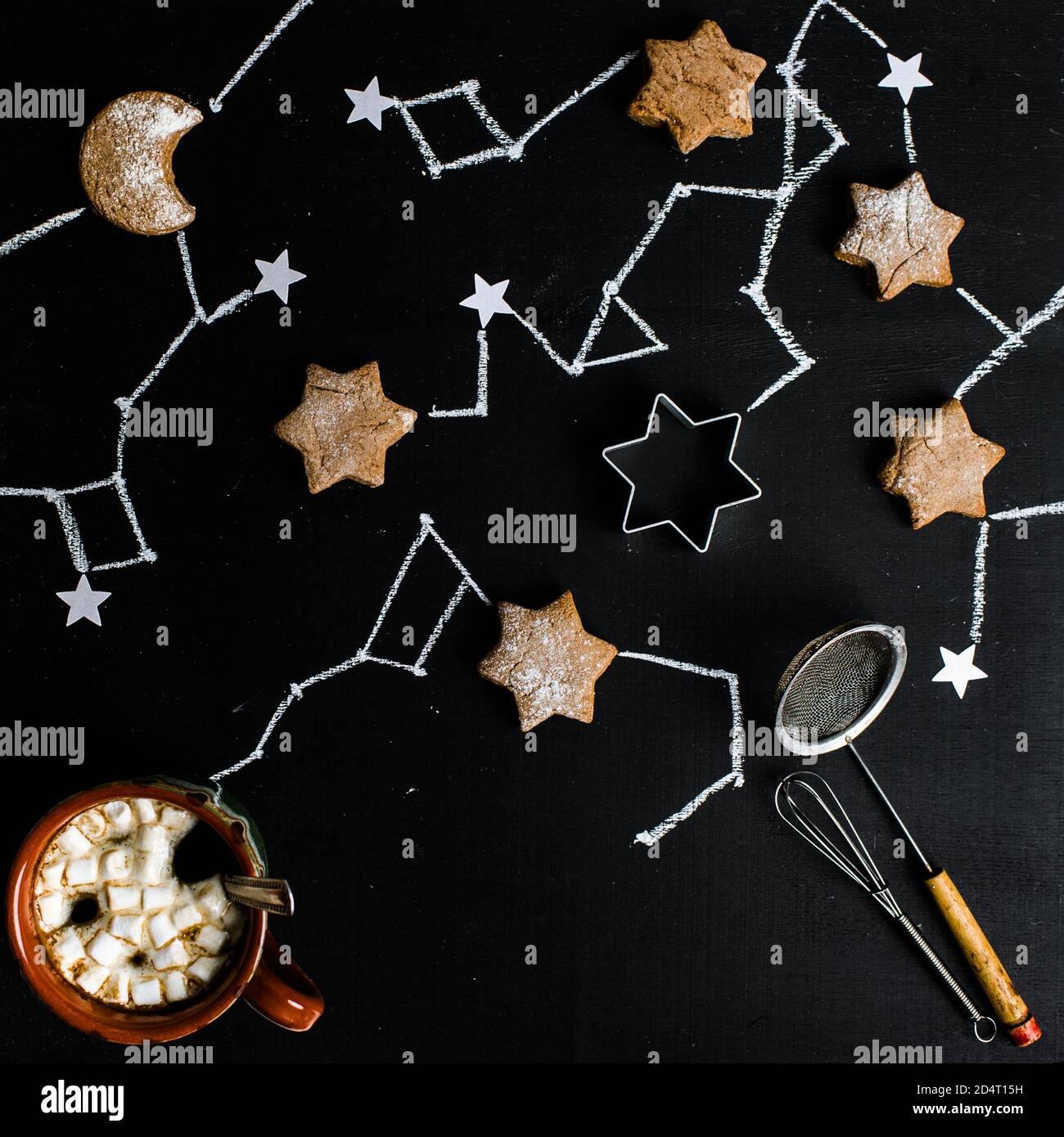 Tazza di caffè con marshmallows su un tavolo su cui i biscotti sono disposti a forma di cielo stellato. Foto Stock