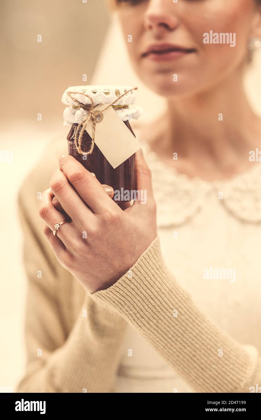 Primo piano di una giara festosa di marmellata nelle mani di una giovane sposa. Stile vintage. Foto Stock