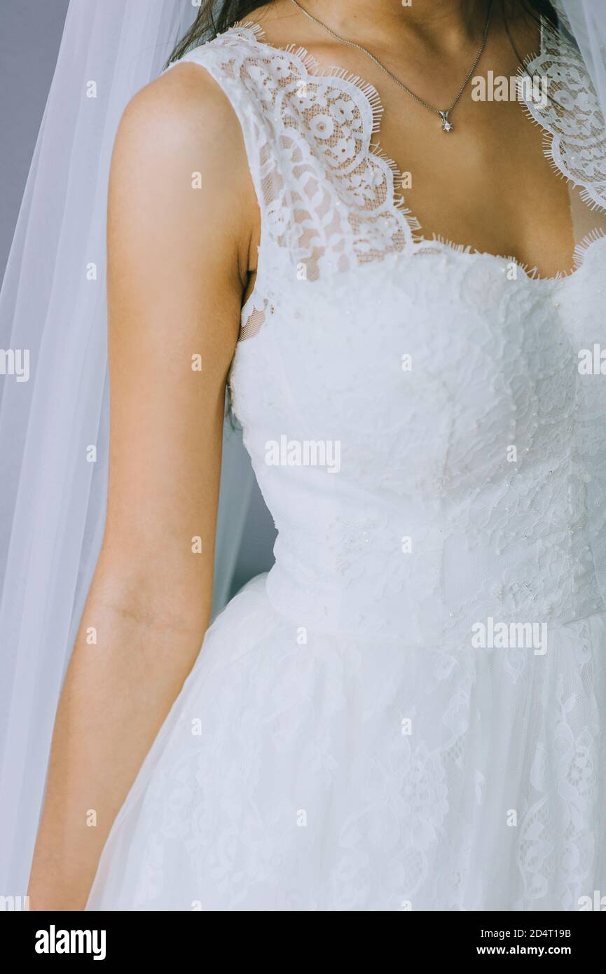 Dettagli di un abito da sposa. Primo piano di ragazza senza volto in bello vestito bianco di nozze. Foto Stock