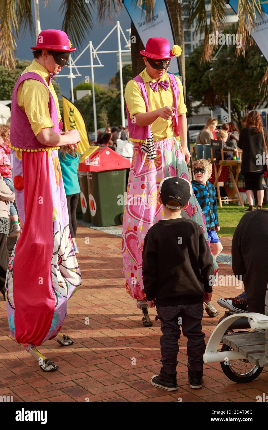 Due palafitte in colorati costumi clown che intrattiene i bambini. Tauranga, Nuova Zelanda, 10/14/2014 Foto Stock