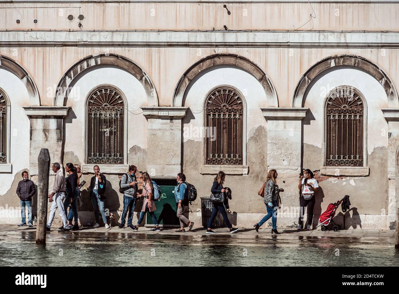 Persone che camminano lungo la stretta strada dei canali allagati a Venezia durante Corona Foto Stock