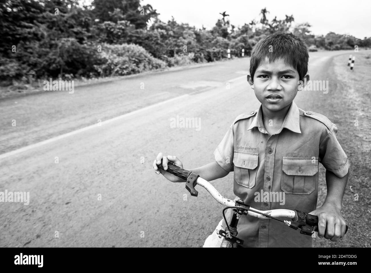 Pakse, Laos - 27 ottobre 2010: Ragazzo laotiano in uniforme scolastica con bicicletta sulla National Highway T 16 da Salavan a Pakse, Laos. Foto Stock