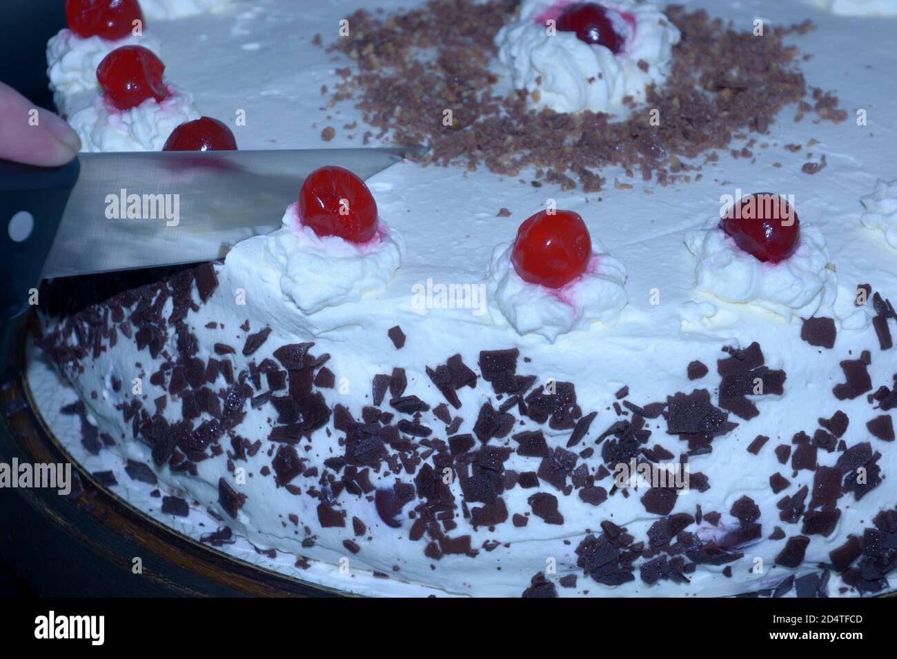 le mani femminili tagliano una deliziosa vista ravvicinata della torta della foresta nera Foto Stock