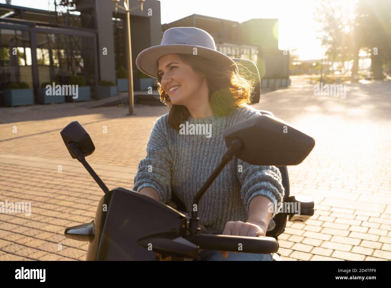 Donna turistica in sella a uno scooter elettrico a quattro ruote su una strada cittadina. Foto Stock