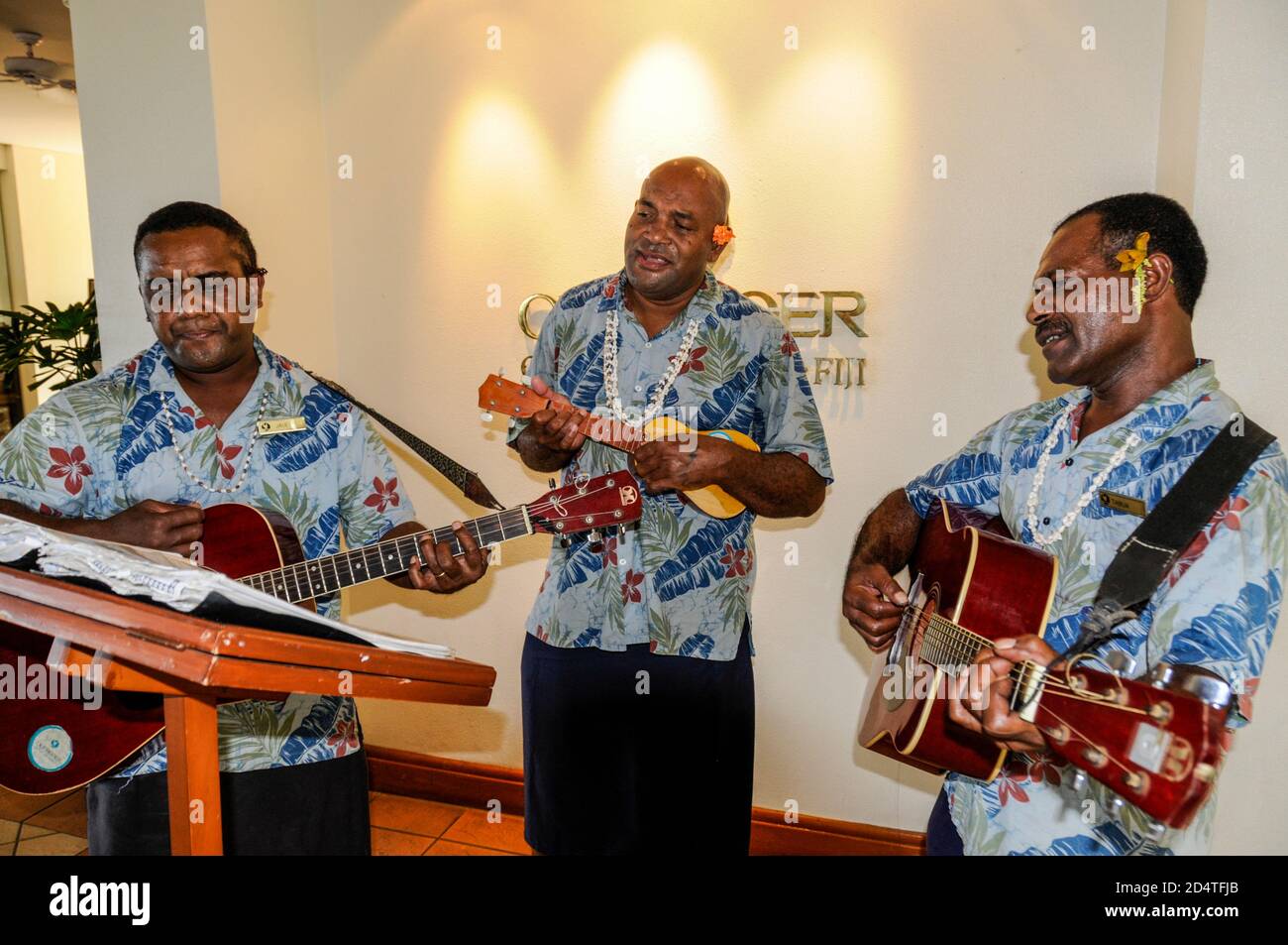 Un trio di musicisti fijiani che entrano in hotel Figi nel Sud Pacifico Foto Stock