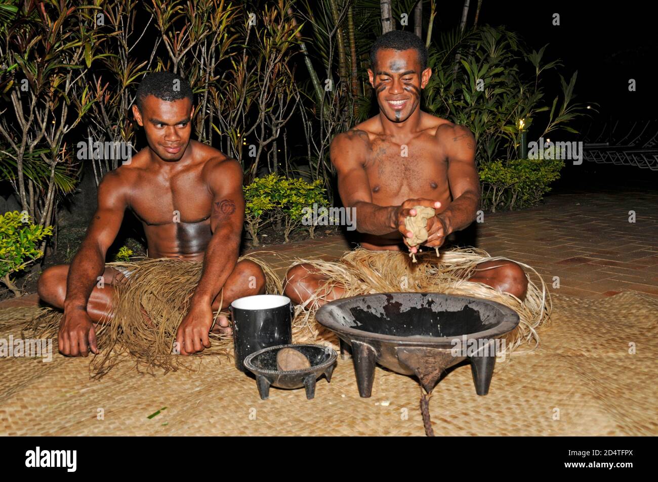 Due fijiani si accovacciano ad uno spettacolo turistico per servire la bevanda nazionale delle Fiji, Yaqona, chiamata anche Kava nelle Fiji nel Pacifico del Sud. Yaqona o Kava Foto Stock