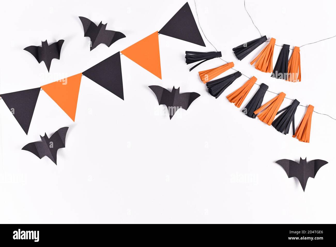 Sfondo di Halloween con ghirlande e pipistrelli di carta in colori tradizionali arancione e nero su sfondo bianco con spazio per la copia Foto Stock