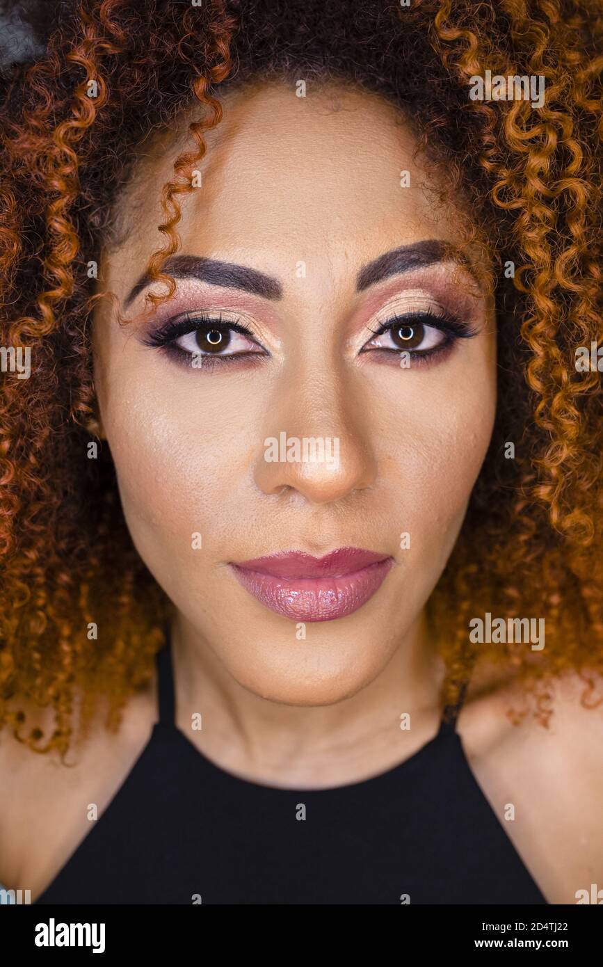 Ritratto di una bella donna afroamericana con un colore rosso arricciato capelli e trucco Foto Stock