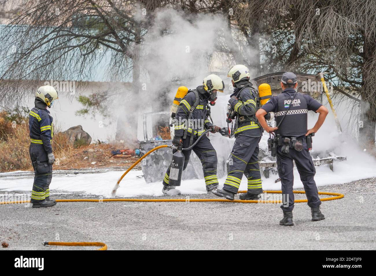 I vigili del fuoco spengono un incendio con schiuma bianca su un'auto in fiamme in una zona forestale, Mijas, Spagna. Foto Stock