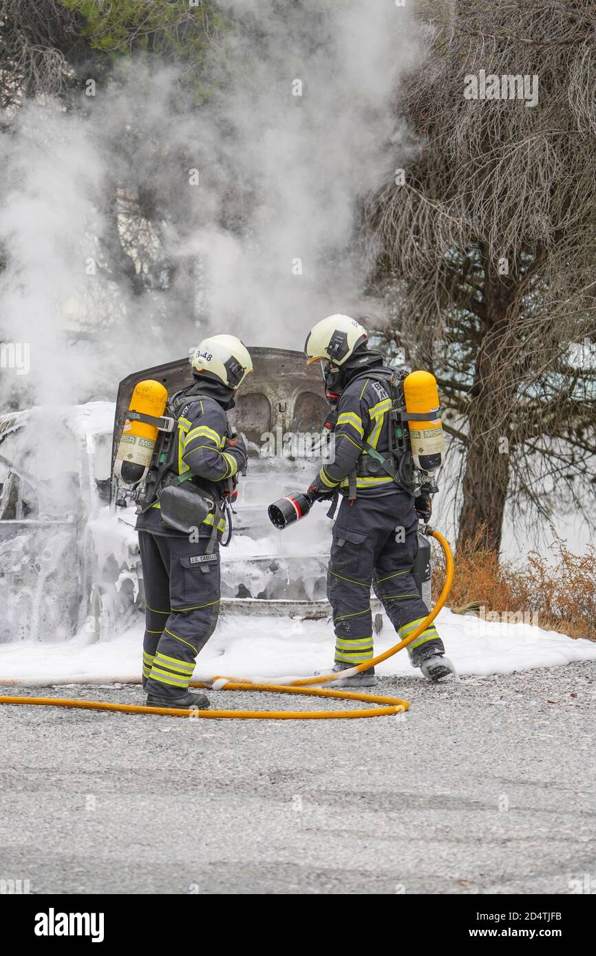 I vigili del fuoco spengono un incendio su un'auto in fiamme in una zona forestale, Mijas, Spagna. Foto Stock