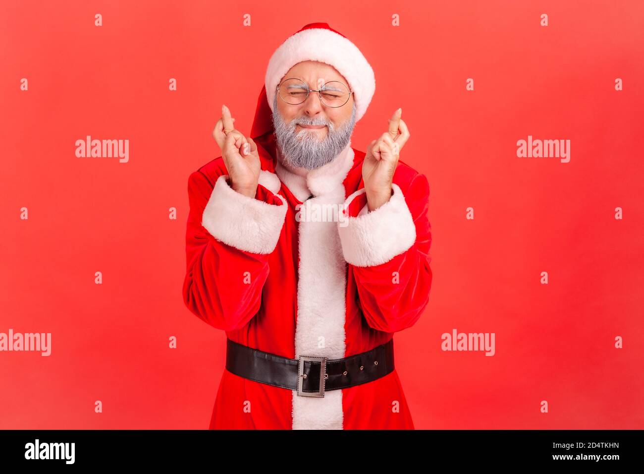 Ritratto di sognante anziano in costume di babbo natale occhi di chiusura e traversata dita fare un desiderio, magia di natale, vacanze invernali. Monolocale interno Foto Stock