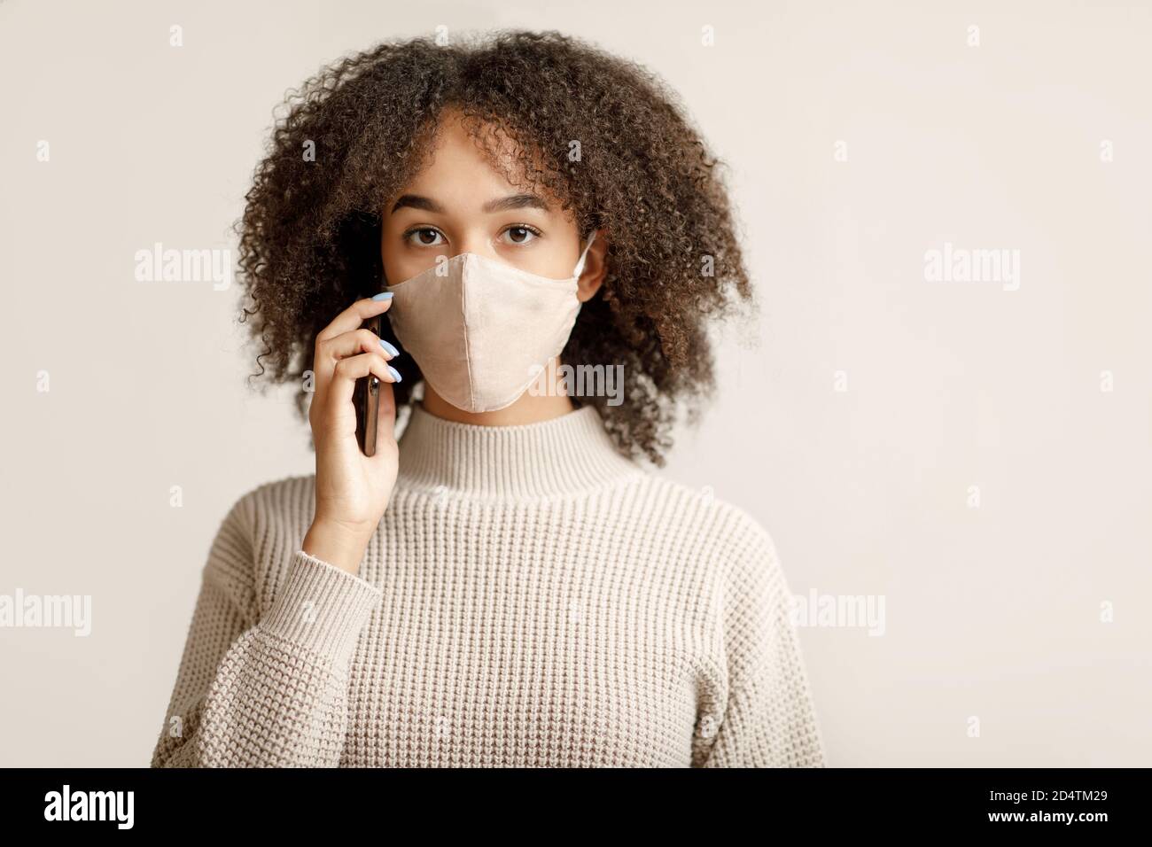 Quarantena, distanza sociale e comunicazione remota. Giovane donna afroamericana che parla al telefono Foto Stock