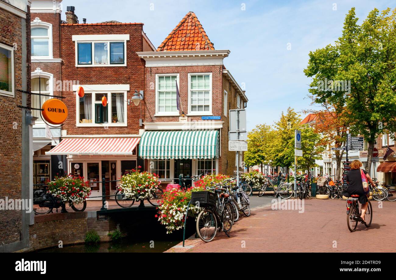 Vista sul centro storico di Gouda. Zeugstraat e Lange Tienderweg con canale, ponte, negozi e case tradizionali in un pomeriggio soleggiato. Hollan del sud Foto Stock