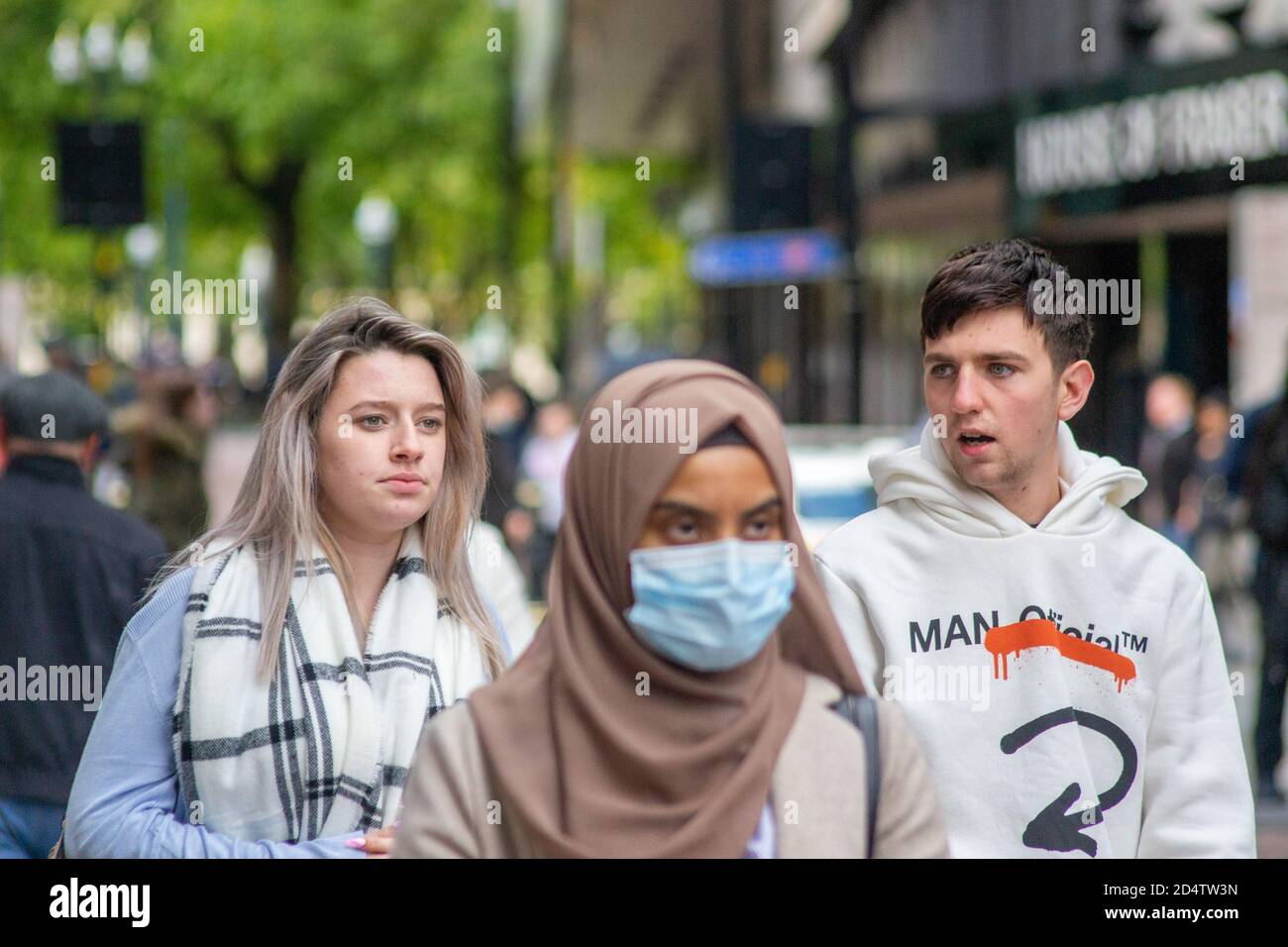 I membri del pubblico passano davanti alla House of Fraser nel centro di Birmingham. Solo una è dotata di maschera facciale per la prevenzione COVID-19 Foto Stock