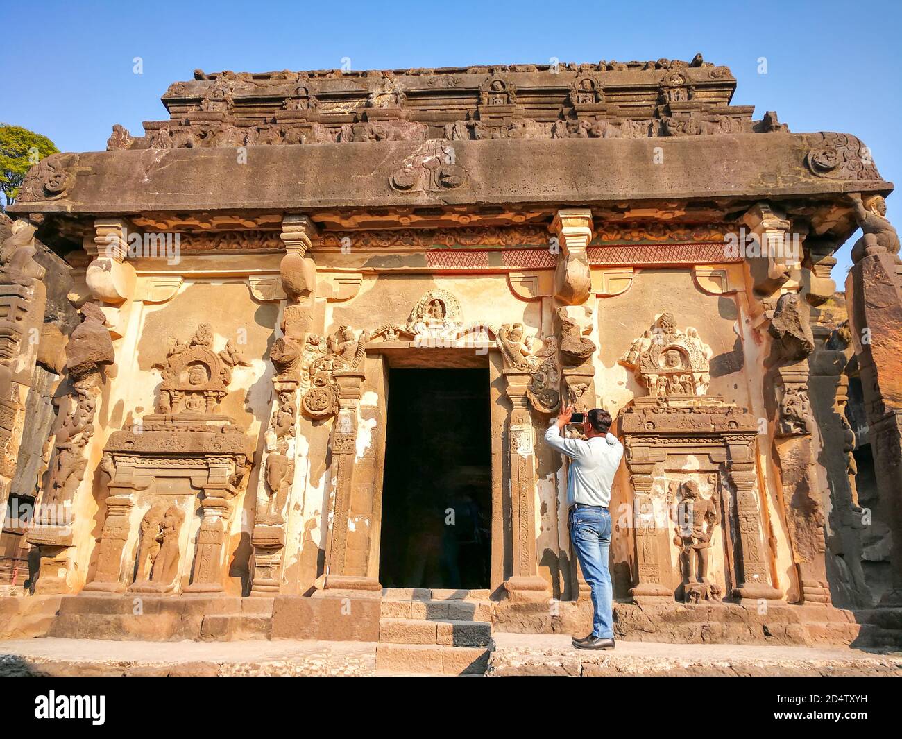 Il turista scatta le foto delle grotte di Ellora nel distretto di Aurangabad di Maharashtra, India, uno dei più grandi complessi rupestri del monastero-tempio scavati nella roccia Foto Stock