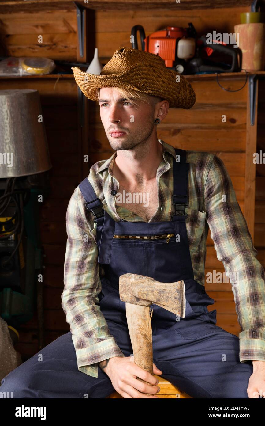 Giovane uomo nei suoi anni 20 indossando delle salse e tenendo un'ascia. Foto Stock