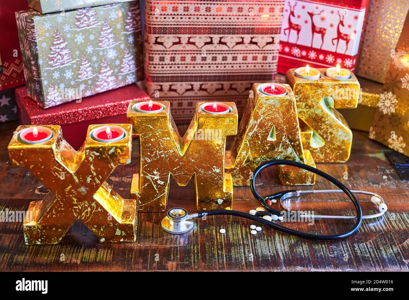Il testo XMAS fatto di lettere d'oro su una superficie di legno combinato con pillole e uno stetoscopio. Foto Stock