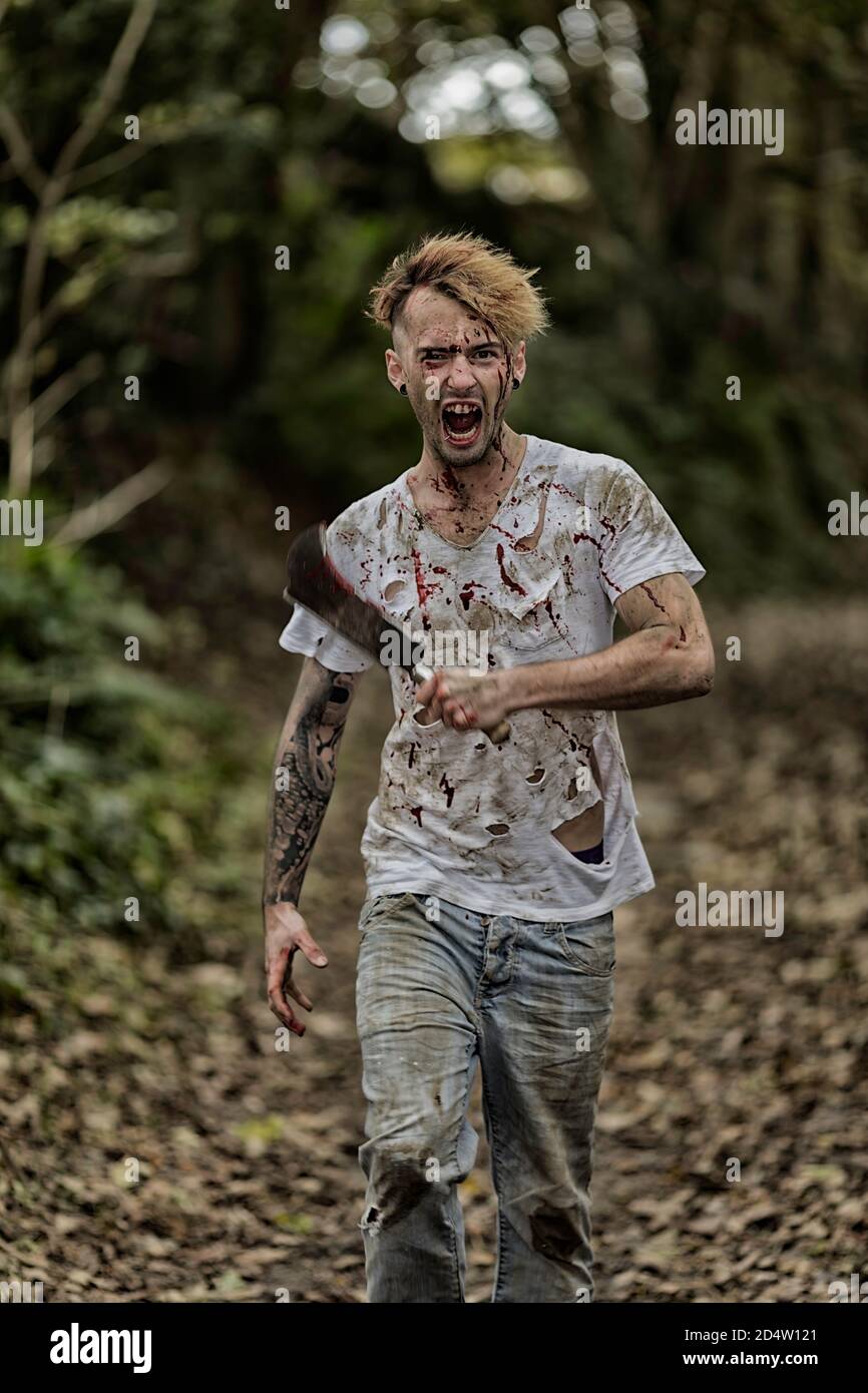 Uomo che indossa una t shirt strappata e sanguinosa e che tiene un falcetto affilato. Sfocatura del movimento Foto stock Alamy