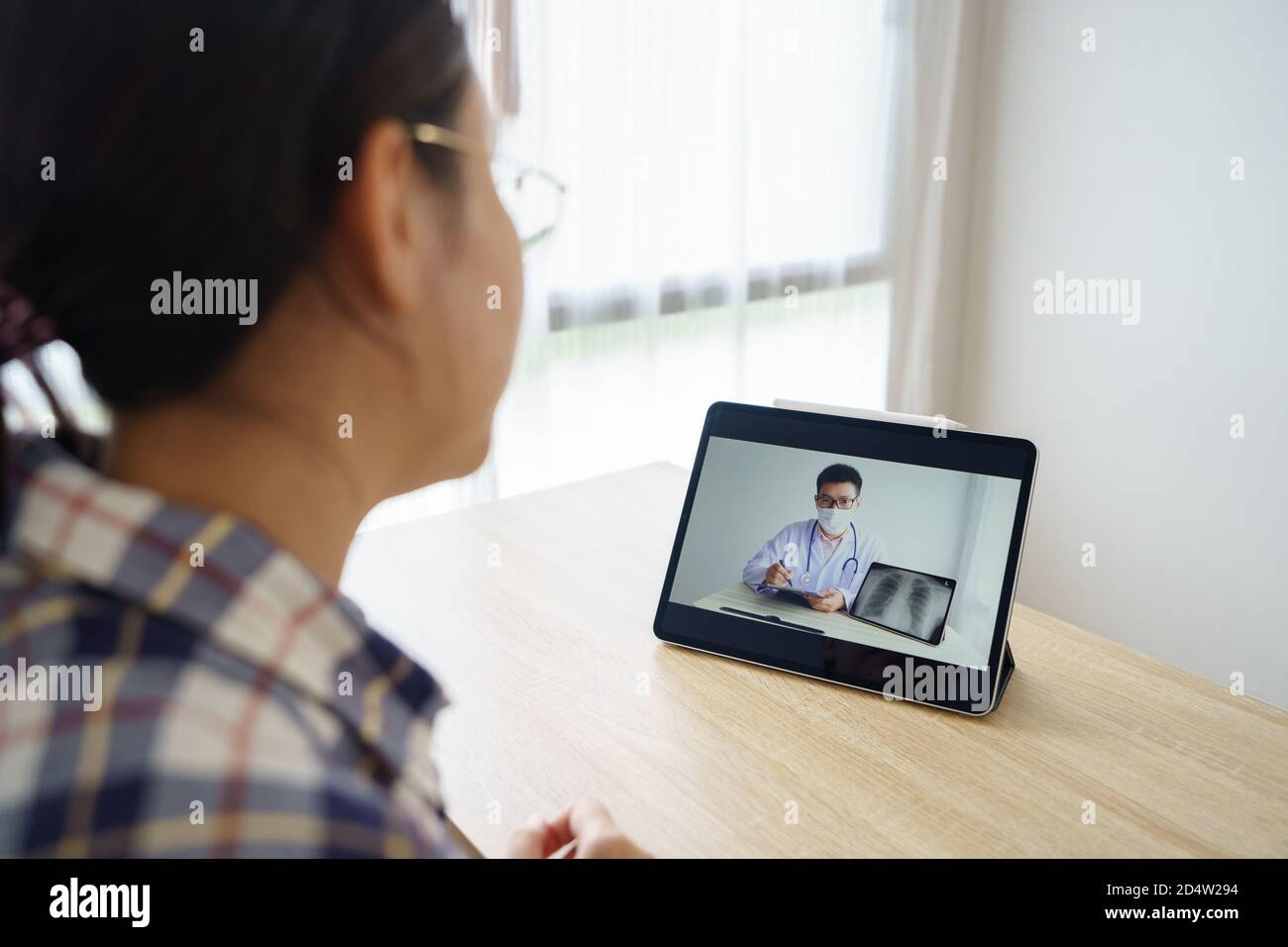 Donna asiatica di 30-35 anni con tablet, Visualizza i risultati degli esami dei medici su un tablet multimediale remoto. Concetto di assistenza e assistenza sanitaria. Foto Stock