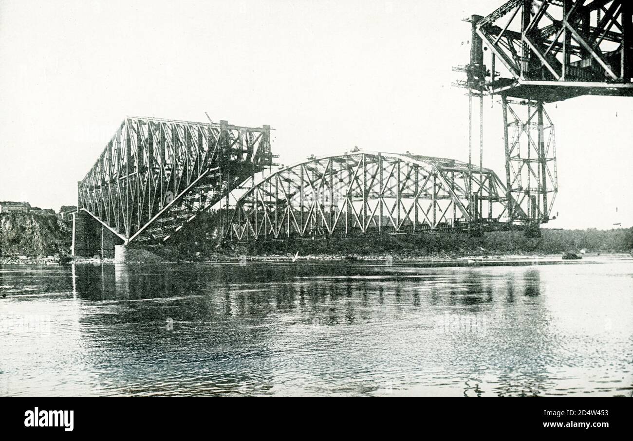 Ponte gigante Cantilever che attraversa il fiume San Lorenzo al Québec. La grande campata di cetner, lunga 640 piedi e del peso di 5,600 tonnellate, è in fase di hposting per completare la struttura. Era un intervallo simile che cadde nel 1916, portando a morte 90 uomini. Il ponte completato è il più grande del suo tipo al mondo, ha un costo di 16,876,000 dollari, è lungo 3,239 piedi, largo 88 piedi e alto 163 piedi dalla base della ferrovia ad alto livello dell'acqua. Porta due binari ferroviari, un vialetto per veicoli e due sentieri in cemento. Foto Stock